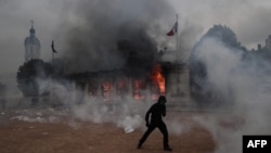Një protestues afër zyrës së turizimit në Lion që u përfshi nga zjarri më 17 tetor 2026. 