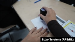 Službenik Izborne komisije pečatira glas građanina na biračkom mjestu u Prištini.