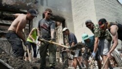 Tineri ucraineni voluntari curăță resturile dintr-o clădire distrusă de o rachetă rusă în timp ce ascultă muzica techno în satul Yahidne, regiunea Cernihiv, Ucraina, duminică, 24 iulie 2022.