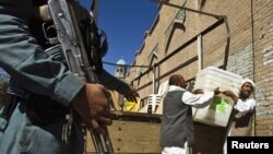 A police officer stands guard as workers carry ballot boxes into a polling station in Jamee mosque in Herat, western Afghanistan