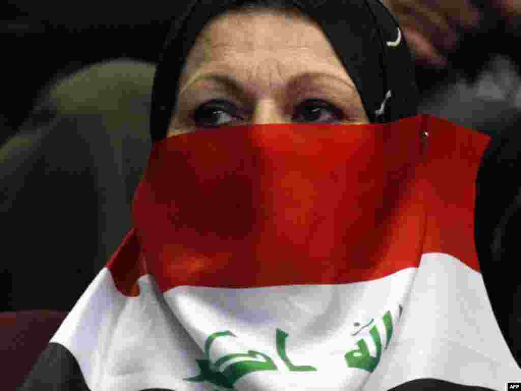 A woman covers her face with the national flag during a ceremony marking Teacher's Day in Baghdad. - Photo by Ahmad al-Rubaye for AFP