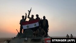 Syrian forces gestures as they carry the national flag in the village of Suway'iah, near the Syrian border town of Albu Kamal, on November 9, 2017. File photo