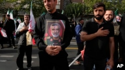 عکس امیرعلی حاجی‌زاده، فرمانده پیشین هوافضای سپاه پاسداران، در دست یکی از هواداران جمهوری اسلامی پس از کشته شدن او در بمباران نیروی هوایی اسرائیل