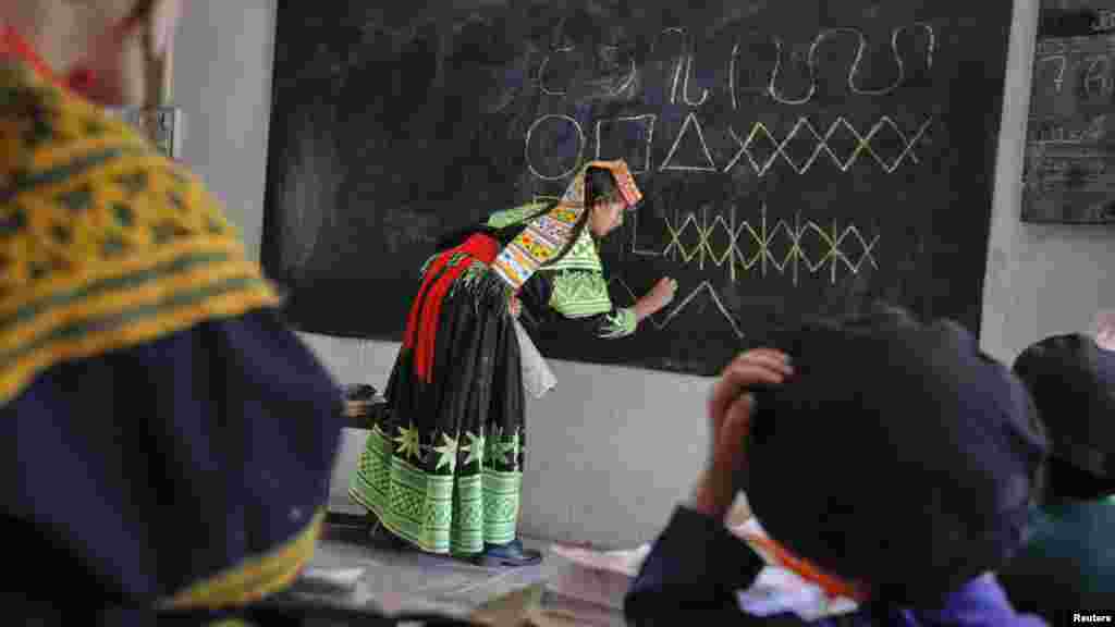 A teacher writes letters from the Kalasha alphabet, used by the Kalash minority, during a lesson in Pakistan&#39;s northwestern Bumboret Kalash valley. 