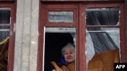Женщина выглядывает в окно после обстрела в Куйбышевском районе Донецка, январь 2015