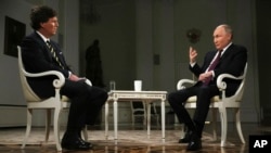Președintele rus Vladimir Putin, în dreapta, în timpul unui interviu cu fostul prezentator Fox News, Tucker Carlson. Interviul a deschis larg ușa propagandei ruse în societatea americană.
