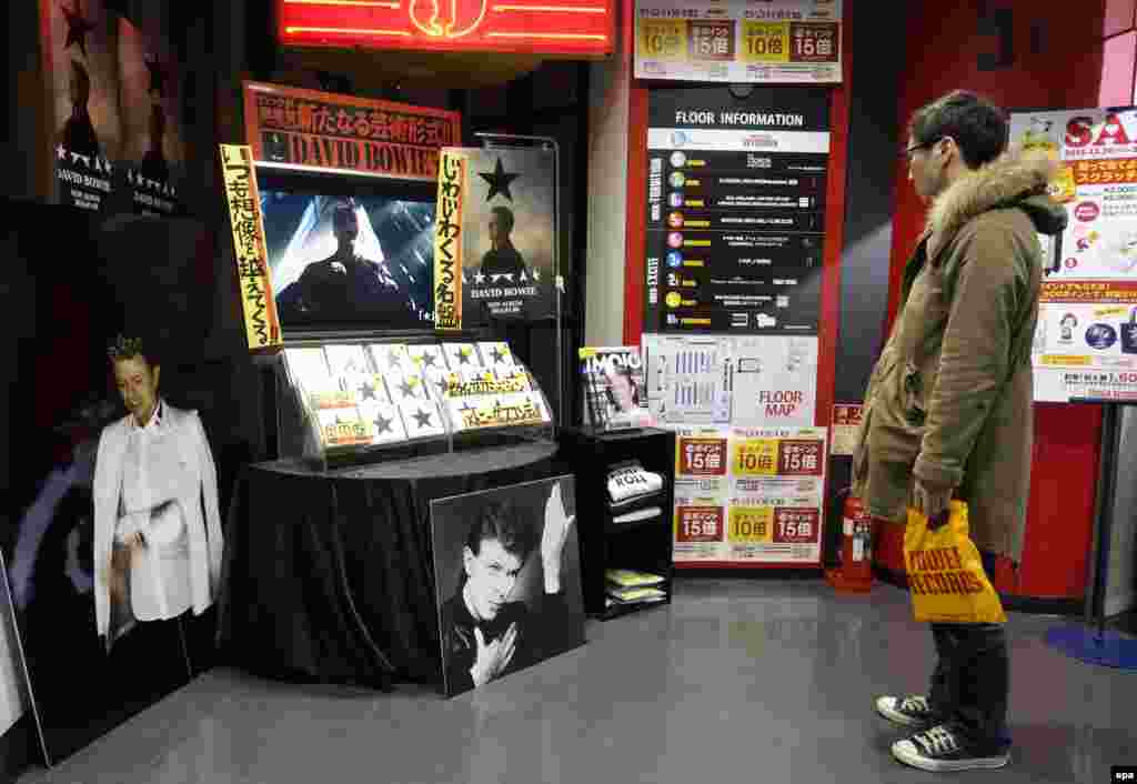 Снимок сделан 11 января 2016 года в день смерти Дэвида Боуи. Покупатель в музыкальном магазине в Токио смотрит на выставленный на витрине последний альбом Боуи &quot;Черная звезда&quot;