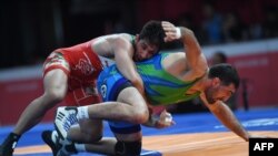 Iran's Hossein Nouri (L) competes with Uzbekistan's Rustam Assakalov in the the men's greco-roman 87kg wrestling gold medal wrestling competition at the 2018 Asian Games in Jakarta on August 22, 2018. / AFP PHOTO / AAMIR QURESHI