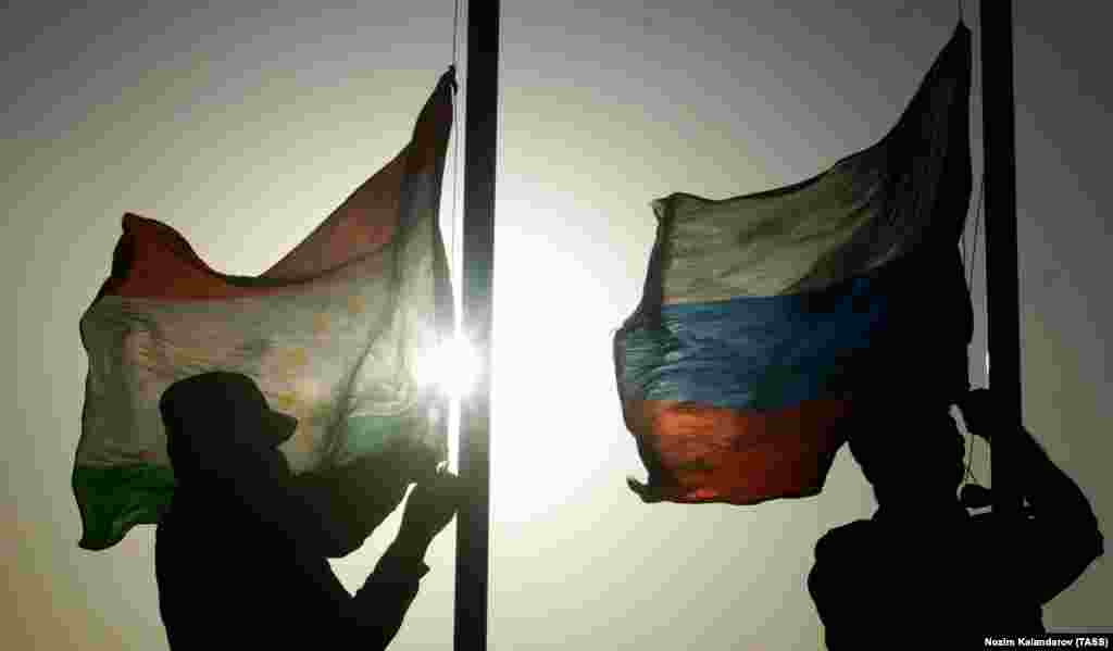 Soldiers raise the flags of Tajikistan (left) and Russia on August 10.