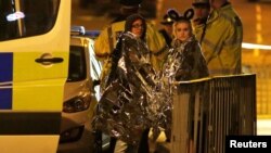 Mançesterde wakanyň bolan ýerindäki adamlar we polisiýa işgärleri.