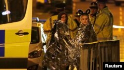 Mançesterde wakanyň bolan ýerindäki adamlar we polisiýa işgärleri.