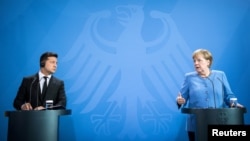 Ukrainian President Volodymyr Zelenskiy (left) and German Chancellor Angela Merkel give statements ahead of talks at the Chancellery in Berlin on July 12.