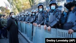 ARMENIA -- A priest stands next to police guarding the National Assembly during a protest against an agreement to halt fighting over Nagorno-Karabakh, in Yerevan, November 11, 2020