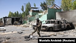 An Afghan soldier stands guard next to damaged army vehicles after a Taliban attack in the southeastren city of Ghazni on August 15.