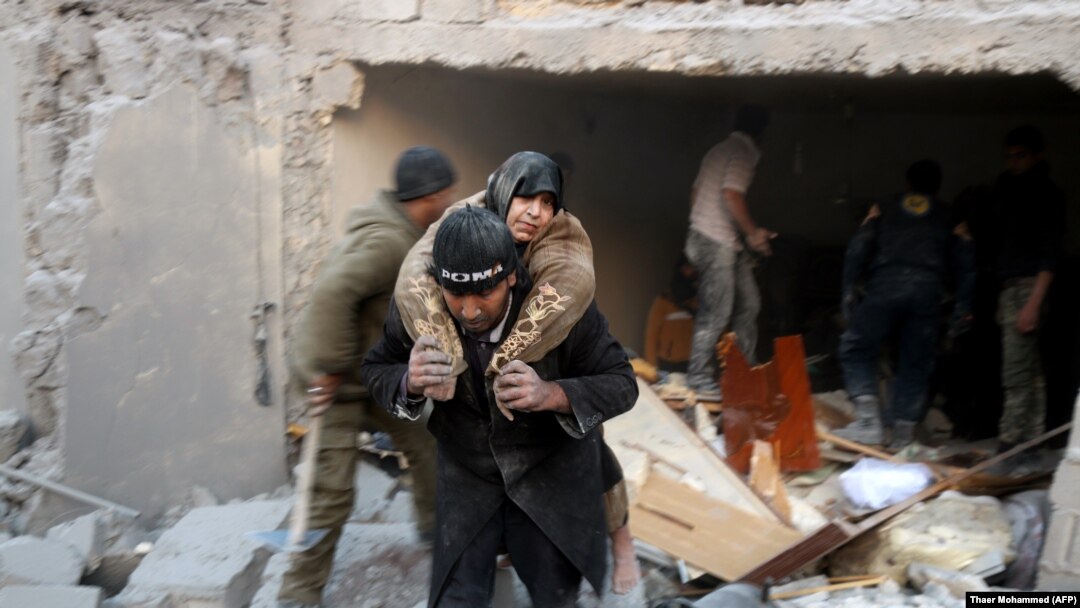 A Syrian rescuer carries a woman who was saved from the rubble of a building following reported air strikes on Aleppo's rebel-held district of Al-Hamra on November 20. 
