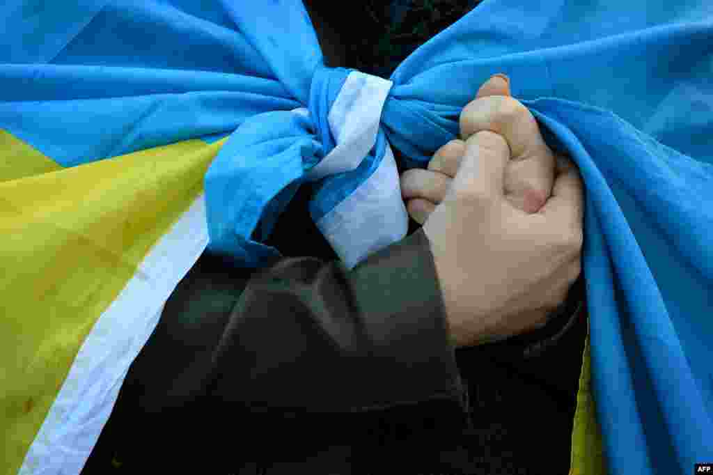 A protester draped in a Ukrainian flag demonstrates against the Russian intervention in Ukraine during a demonstration in London&#39;s Parliament Squareon March 3. (AFP/Ben Stansall)