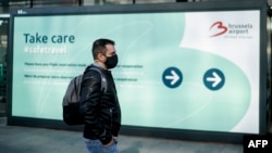 Putnik na aerodromu u Briselu prolazi pored plakata na kojem piše: "Čuvajte se. Sigurno putujte", 15, juni 2020.
