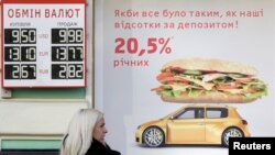 A woman speaks on the phone near a board with currency exchange rates in Kyiv, February 26, 2014