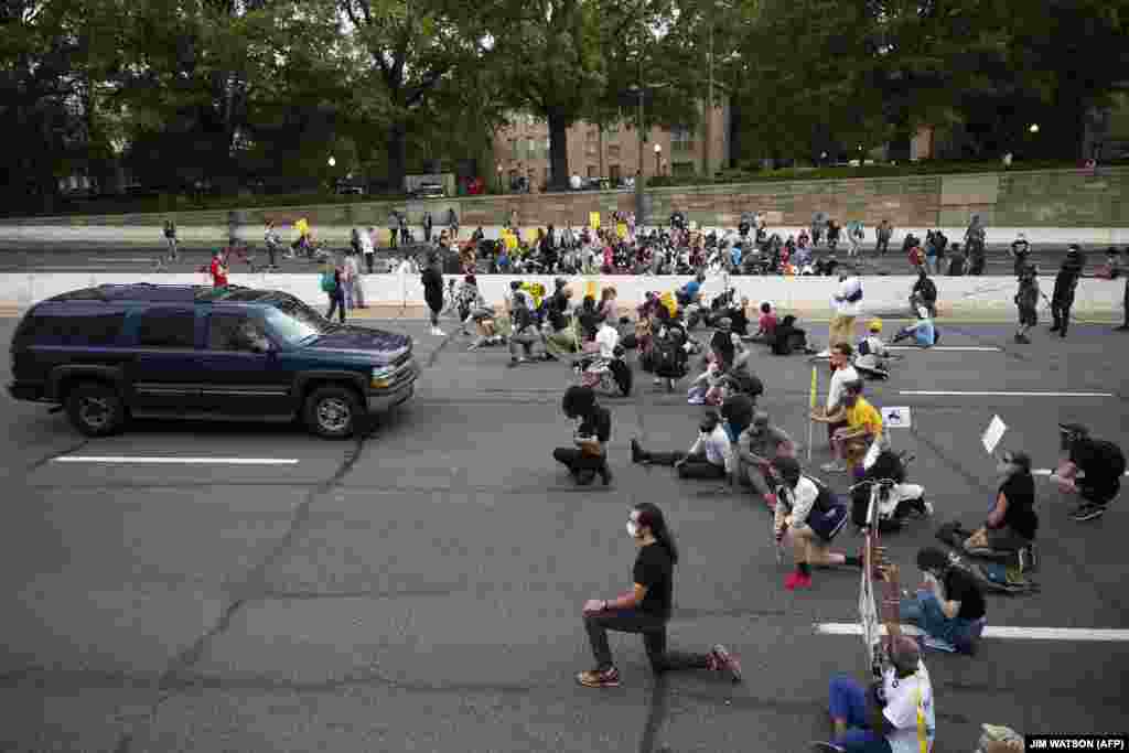 Протестувальники стоять на колінах і тримають плакати, блокуючи рух транспорту. Вашингтон, округ Колумбія, США
