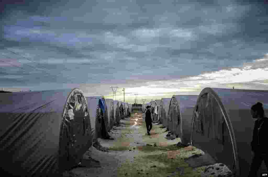 Kurds&nbsp;walk in a refugee camp early in the morning in the town of Suruc, Sanliurfa Province, Turkey. (AFP/Bulent Kilic)