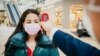 KAZAKHSTAN -- A worker checks the body temperature of a woman as a preventive measure against the COVID-19 coronavirus at a shopping ma in Nur-Sultan, May 4, 2020