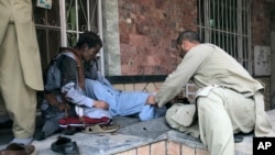 AFGHANISTAN -- People attend to a man injured in a blast in the Afghanistan's Balkh Province on March 11. AP Photo. 
