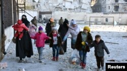 Civilians who evacuated the eastern districts of Aleppo carry their belongings as they arrive in a government-held area on December 7.