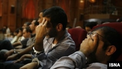 Iranian opposition suspects cover their faces during their second hearing at a revolutionary court in Tehran on August 8.