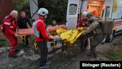 Medics carry a wounded person to an ambulance at the site of destroyed private houses hit during a Russian drone strike on Zaporizhzhya.