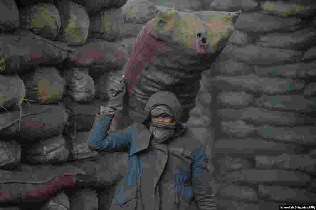 An Afghan laborer unloads a sack of coal from a truck at a coal yard in Kabul. (AFP/Noorullah Shirzada)