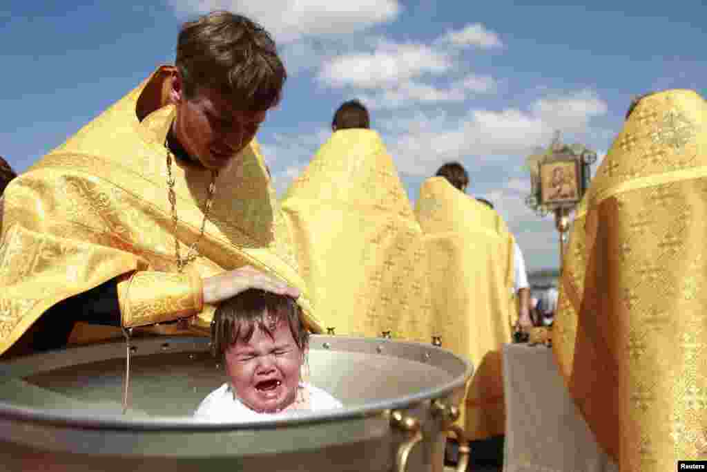 A priest baptizes a child at Novopyatigorsk Lake near the southern Russian town of Pyatigorsk. About 80 people were baptized by the Russian Orthodox Church during the ceremony. (Reuters/Eduard Korniyenko)