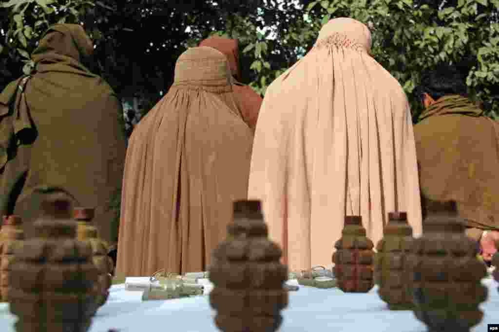 Former Taliban fighters, including two women, stand handcuffed near seized weapons at a police headquarters after a military operation in Afghanistan&#39;s Nangarhar Province on February 4, 2014. (Abdul Mueed, epa)