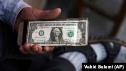 An Iranian street money changer holds a U.S. banknote in downtown Tehran, July 30, 2018