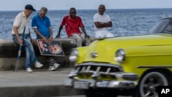 گروهی از شهروندان کوبایی با پوستر فیدل کاسترو، رهبر پیشین کشور، در ساحل هاوانا