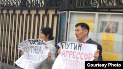 Жарандык активист Нурлан Карымшаков менен жубайы Гүлзана Имаева Орусия элчилигинин алдында пикетте. Бишкек. 27-март, 2019-жыл. (Сүрөт Карымшаковдун «Фейсбуктагы» баракчасынан алынды).