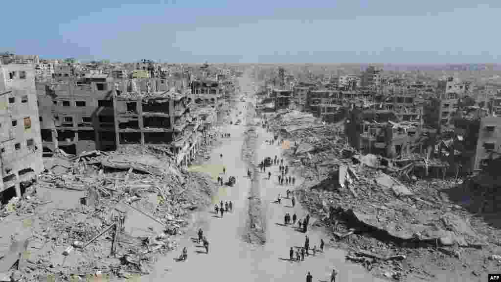 11 octombrie 2025, Gaza, a doua zi după intrarea în vigoare a armistițiului care a dus, două zile mai târziu, la semnarea acordului de pace.Oamenii merg printre ruinele principalei așezări a fâșiei de pământ pe care Israelul a atacat-o constant în ultimii doi ani cu scopul de a distruge Hamas, gruparea desemnată teroristă de SUA și UE, după atacul-surpriză din 7 octombrie 2023.