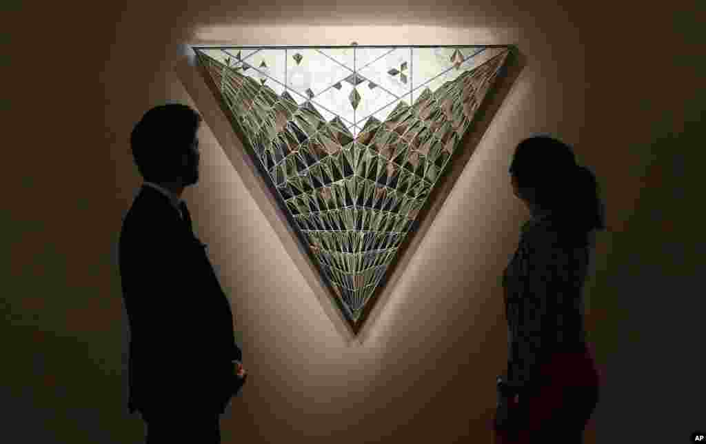 Visitors look at the 'Triangle of Hope' by Monir Farmanfarmaian as part of the Middle Eastern Art auction at the auction house Sotheby's in London, Friday, April 21, 2017. (AP Photo/Frank Augstein)