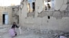 Iran -- An earthquake victim carries a few belongings as she walks next toa severly damaged house in the city of Varzeqan, north-western province of East Azerbaijan, 13Aug2012