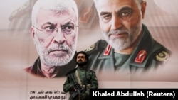 A Houthi militant stands by a billboard with posters of Iraqi militia commander Abu Mahdi al-Muhandis and Iranian military commander Qassem Soleimani during a rally by Houthi supporters to denounce the U.S. killing of both commanders, in Sanaa, January 6, 2020.