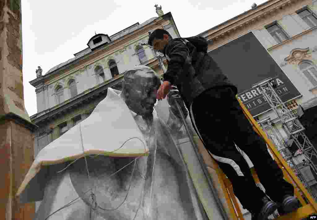 A worker unwraps a statue of late Pope John Paul II in front of The Cathedral of The Heart Of Jesus Christ in Sarajevo. (AFP/Elvis Barukcic)