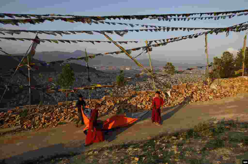 Buddhist children carry a tent after their monastery was damaged following the deadly earthquake in Kathmandu, Nepal. (epa/Narendra Shrestha)