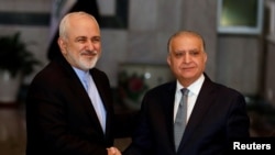 Iraqi Foreign Minister Mohamed Ali Alhakim shakes hands with his Iranian counterpart Mohammad Javad Zarif after a news conference, in Baghdad, Iraq March 10, 2019. REUTERS/Khalid Al-Mousily