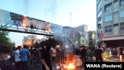 Një pankartë që duket se promovonte organizatën paramilitare Basij të Iranit u dogj gjatë protestave në Teheran pas vdekjes së Mahsa Aminit në shtator 2022.