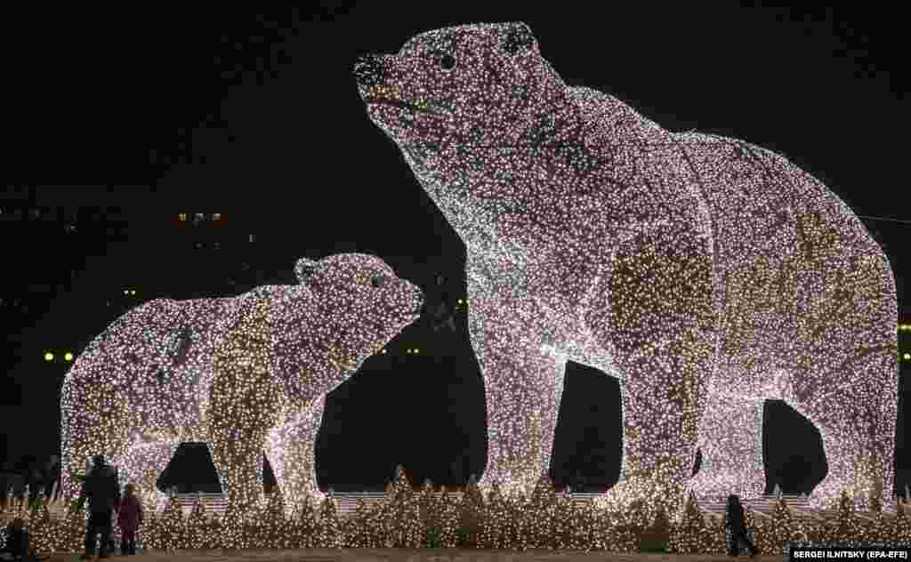 People walk near huge light sculptures in the shape of polar bears in Moscow on December 14.