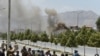 Afghan security personnel and bystanders look on as black smoke billows from the Afghan Parliament building in Kabul on June 22.