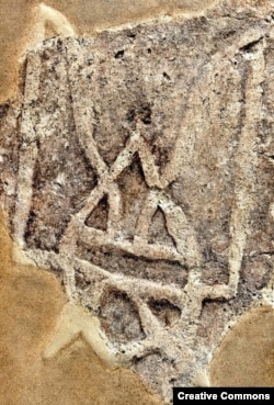 Тризуб X століття, знайдений на уламку цеглини на руїнах Десятинної церкви в Києві. Дехто вважє, що цей символ імітує сокола, який кидається вниз, або символізує Святу Трійцю