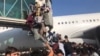 Desperate Afghans attempt to board a plane at Hamid Karzai airport in Kabul on August 16 after the Taliban had seized the city. 