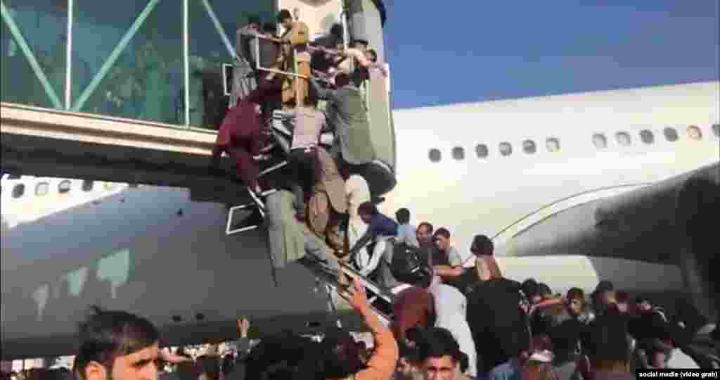 Desperate Afghans attempt to board a plane at the airport in Kabul.