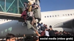 People try to board a plane at the airport in Kabul on August 16.