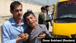 Ýaş oglan Kabuldaky toýa edilen hüjümde ölen doganynyň matamyny tutýar. 18-nji awgust, 2019 ý.